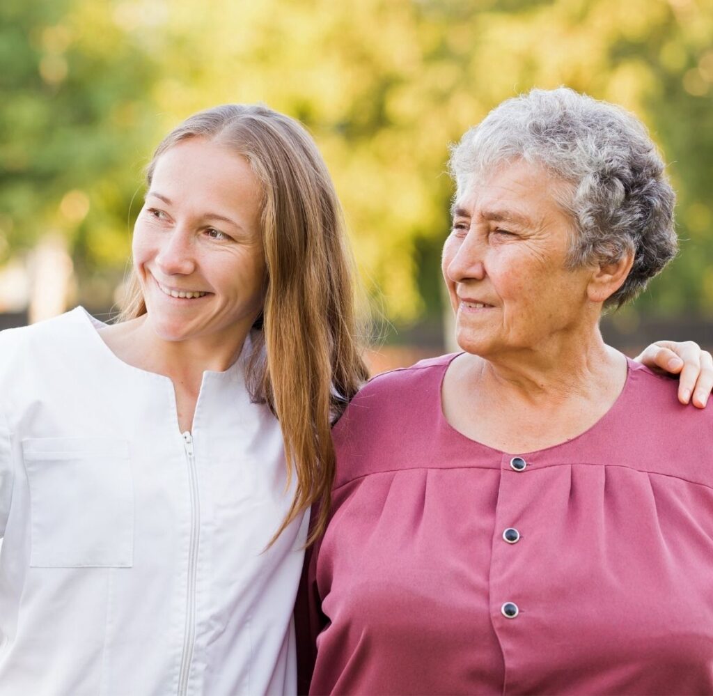 Caregiver Accompanying Elderly Woman on an Outdoor Walk Caregiver walking beside an elderly woman outdoors while offering gentle support and companionship.