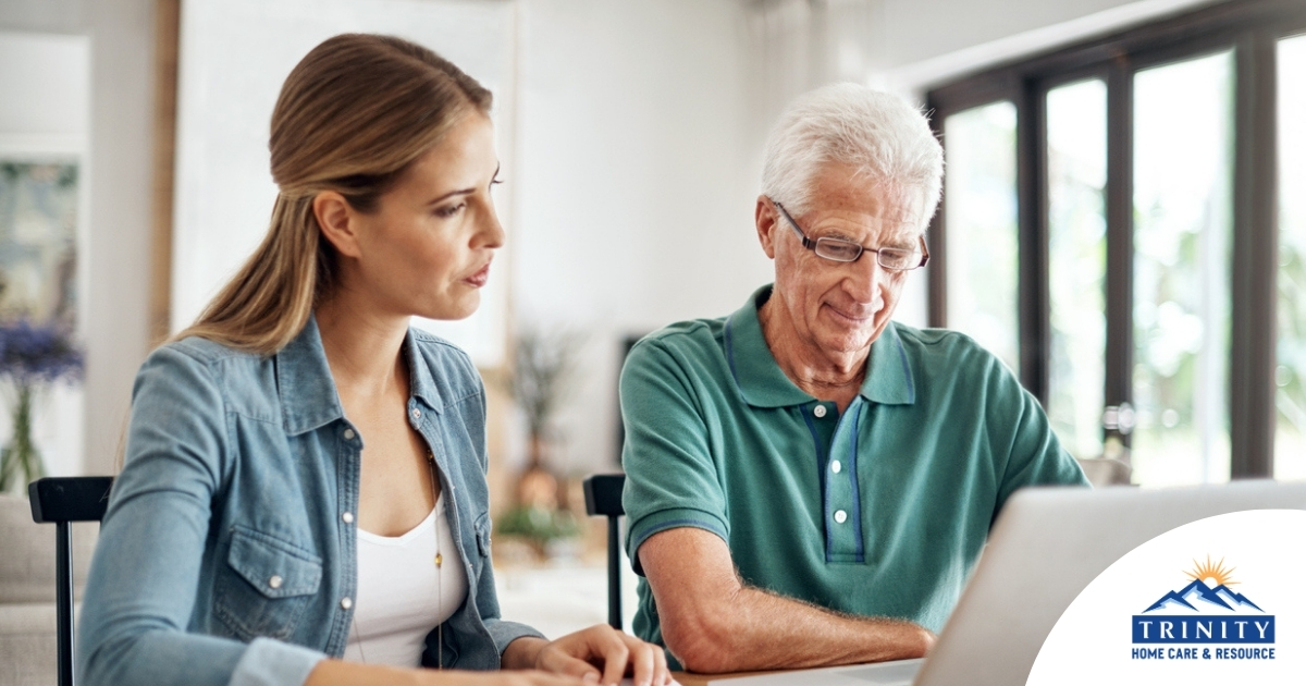 Adult daughter and senior father talking at a kitchen table while comparing home care vs assisted living
